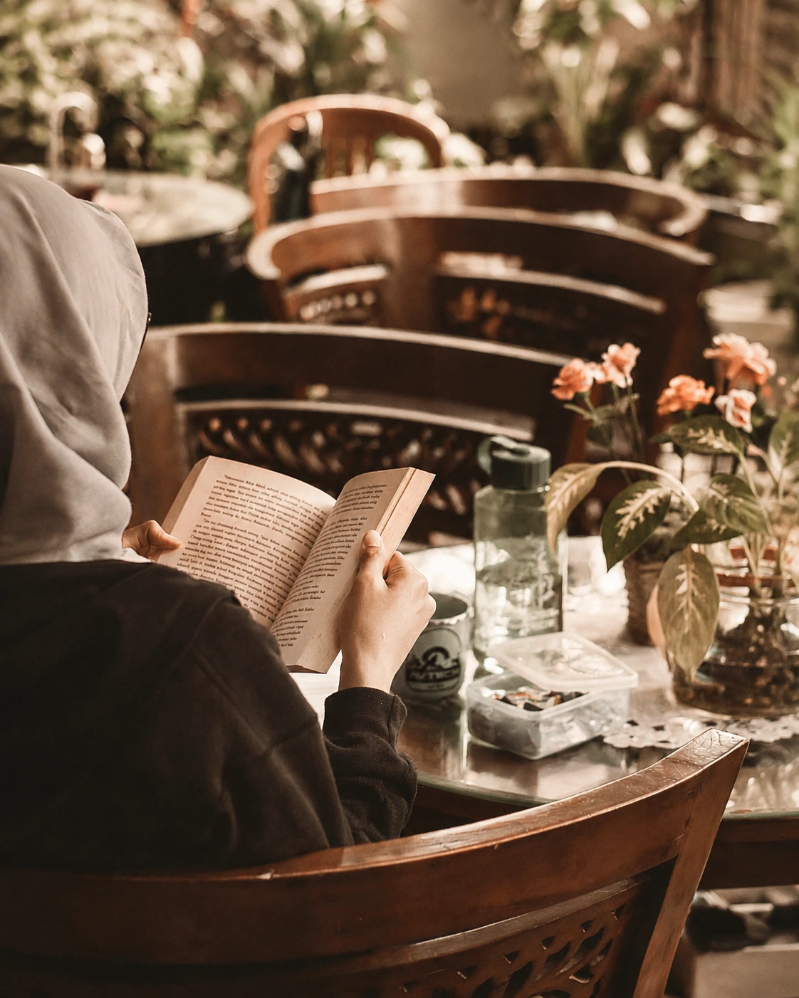 Persona leyendo en un café rodeado de plantas